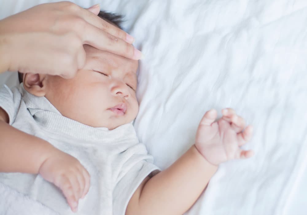 Vuxen som känner på bebis panna