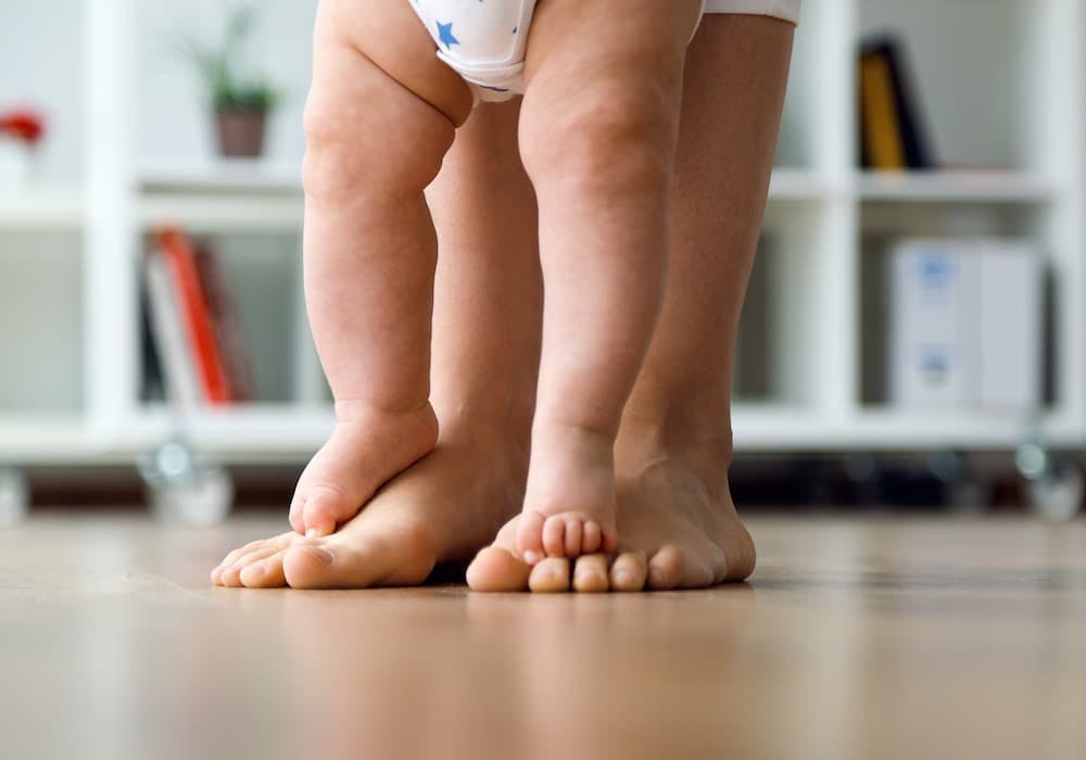 bebisfötter går på på vuxens fötter