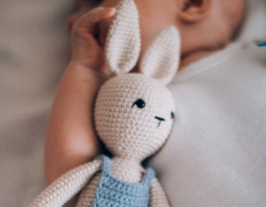 Liten bebis med uppstoppad kaningosedjur