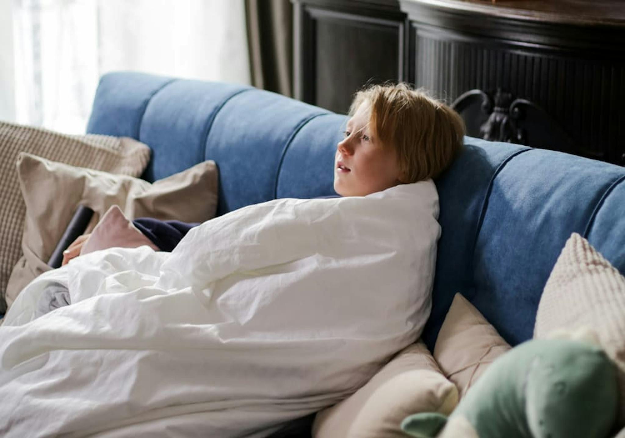 pojke som sitter i en soffa inlindad i ett täcke
