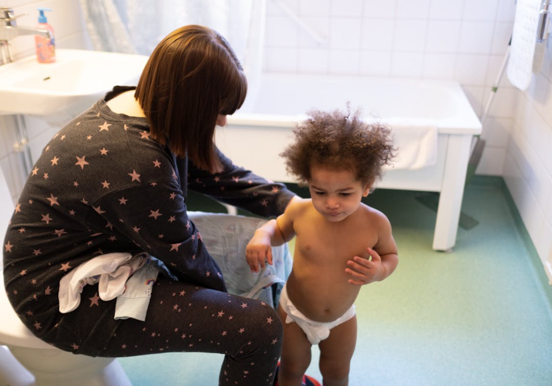 En mamma och ett barn med blöja i badrummet.