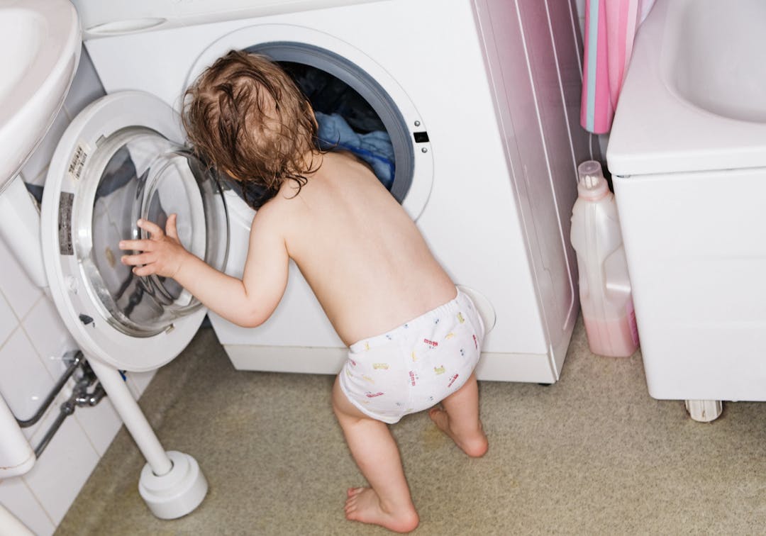 barn framför tvättmaskin
