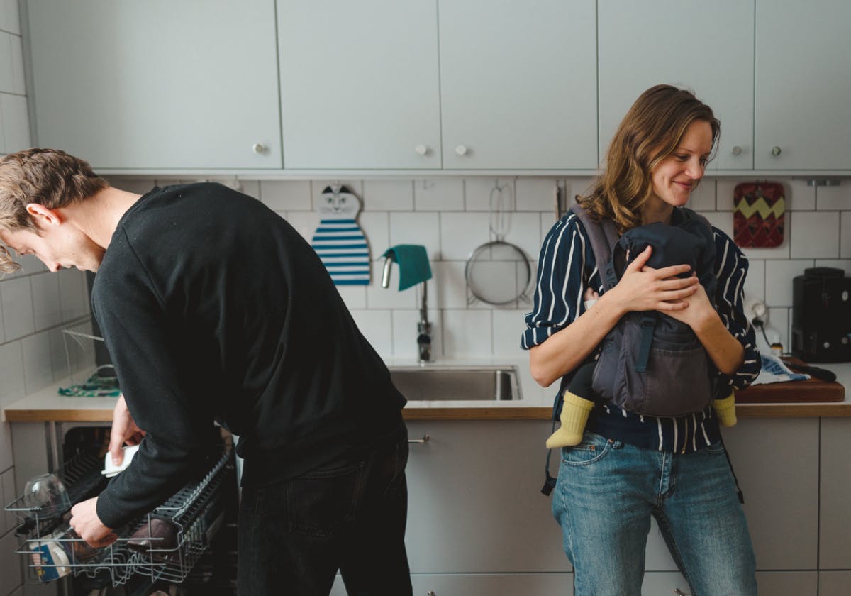 Föräldrar i kök med barn i bärsele