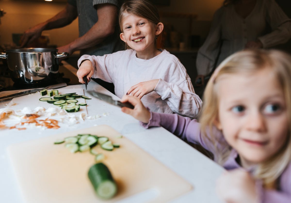 Glada barn skär upp grönsaker