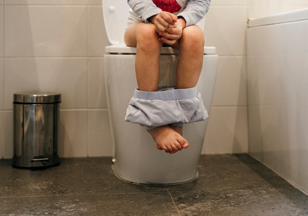 Barn sitter på toalettstol