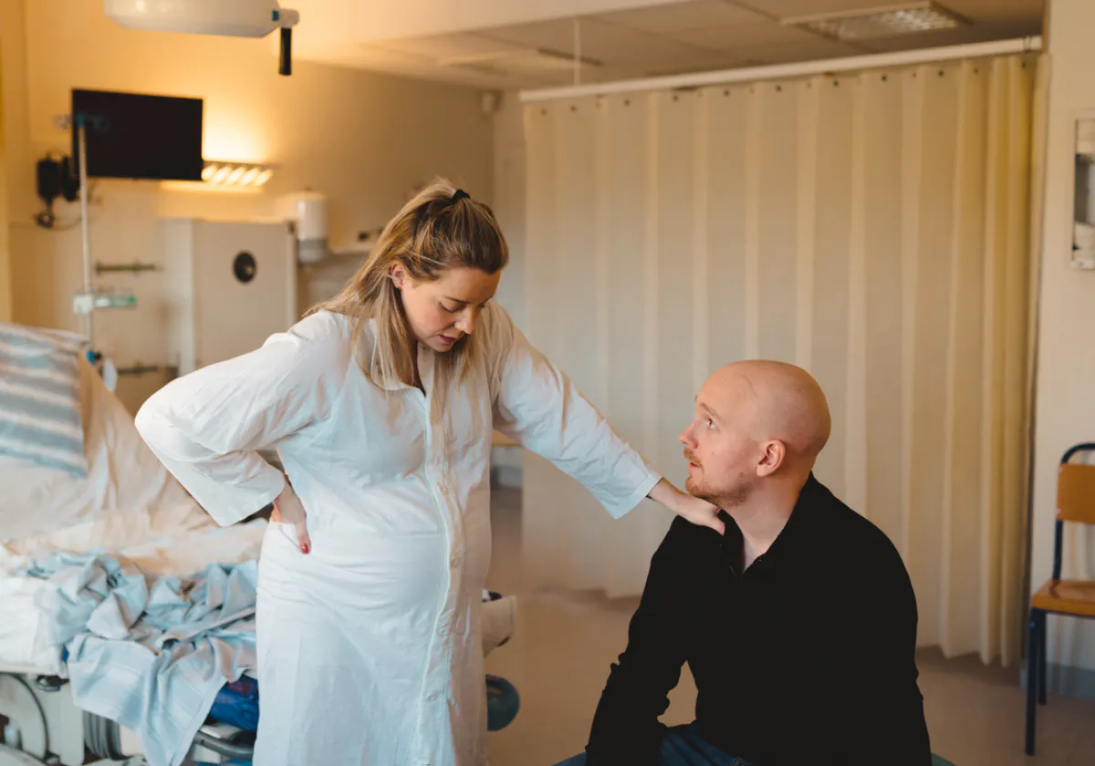 Gravid kvinna upplever värkar och lutar sig mot sin partner för stöd