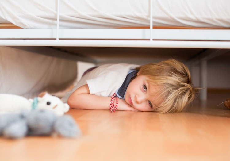 barn som gömmer sig under sängen