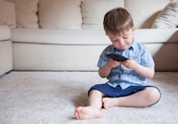 Pojke som sitter på golvet och tittar på en mobiltelefon
