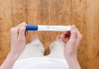 bild tagen uppifrån på kvinna som håller i ett positivt graviditetstest