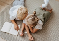 pojke och flicka som ligger på golvet och skriver i en bok