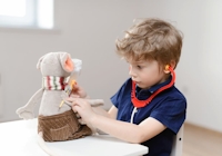 Liten pojke med låtsas-stetoskop som tar tempen på ett gosedjur