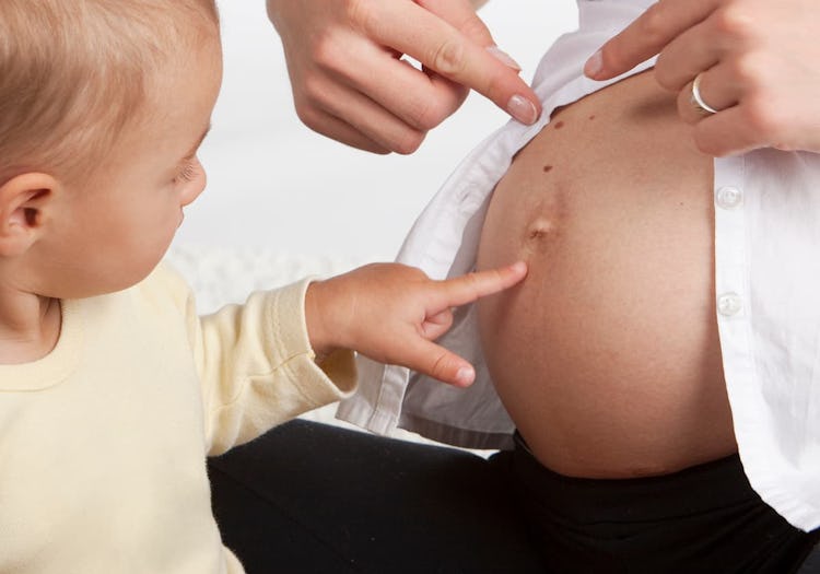 bebis som pekar på gravidmage