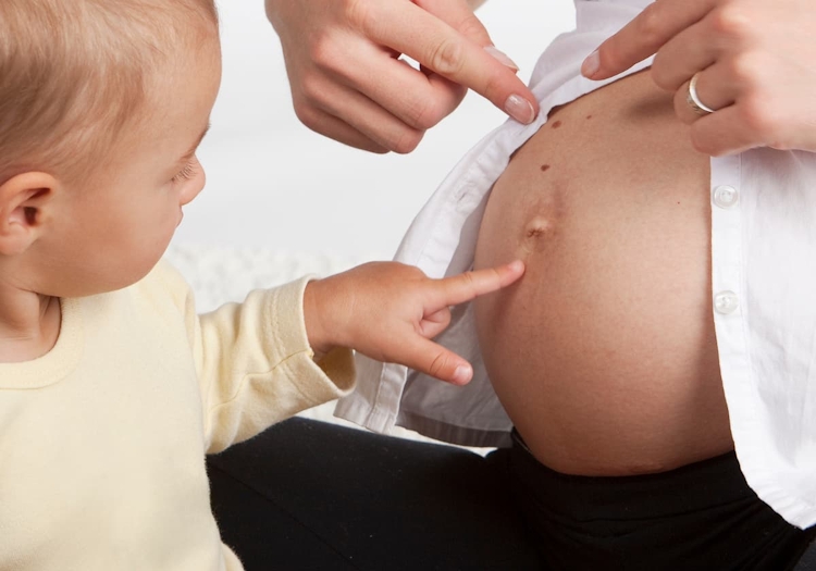 bebis som pekar på gravidmage