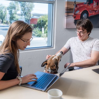 Two Kodiak employees and a dog in a work setting