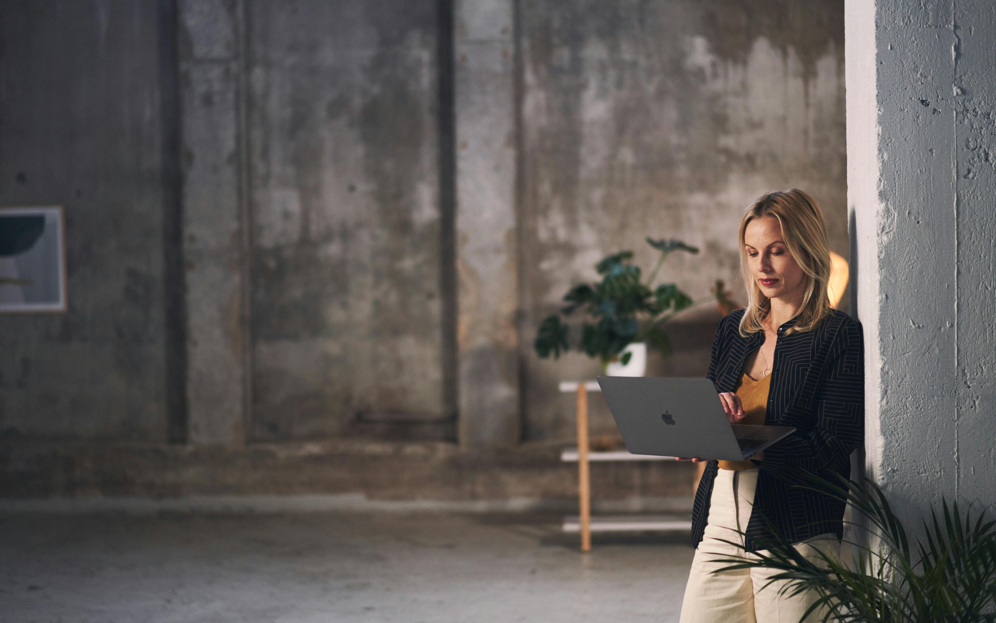 Woman using a laptop computer by a wall