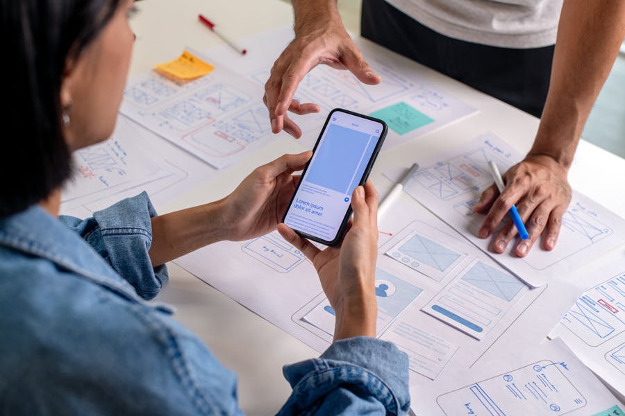 ui-designer-checking-mobile-design-on-table-some-sketches