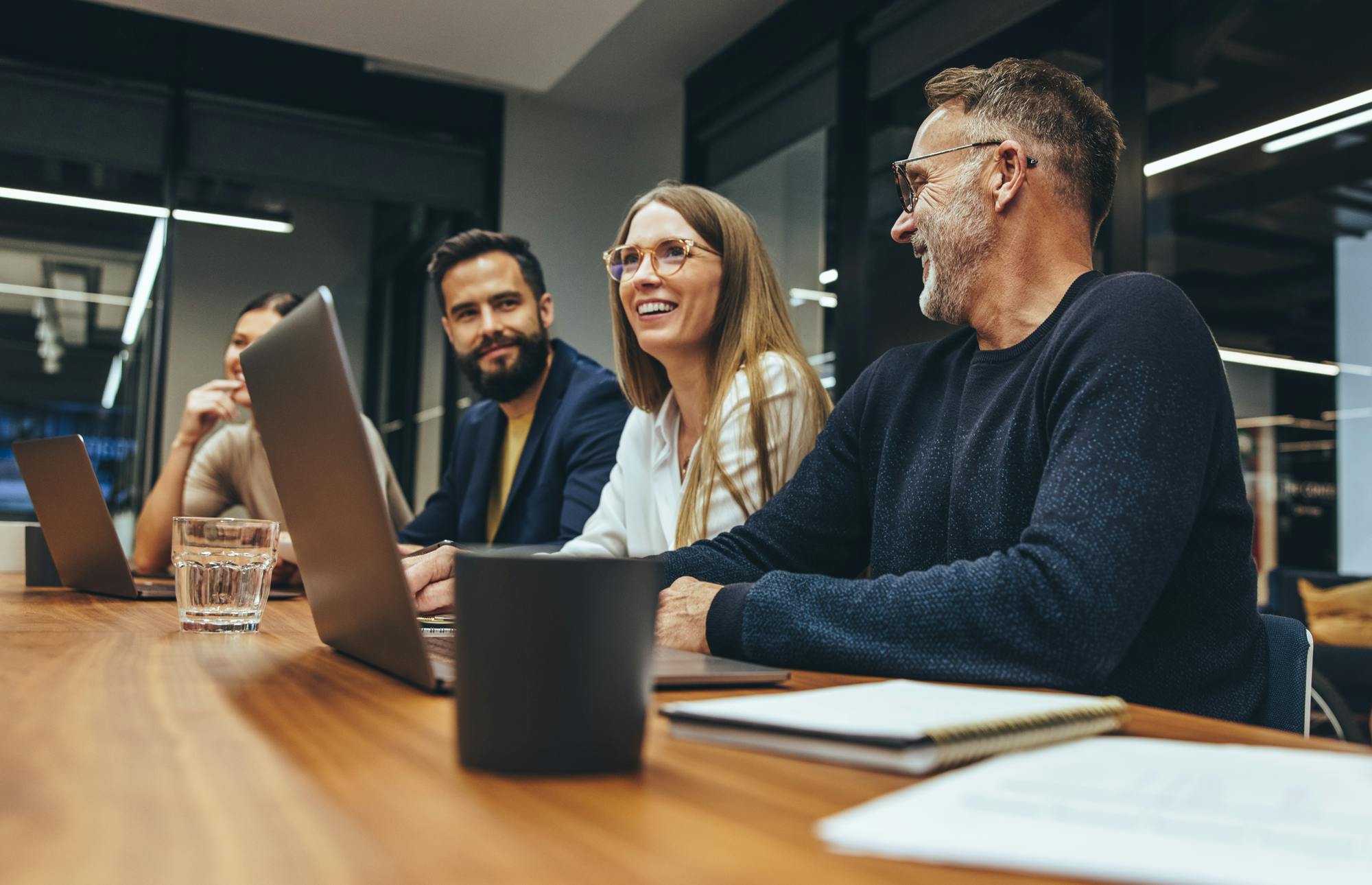 konferensrum-man-ser-fyra-personer-de-ler och har lap toppar uppfällda på bordet framför dem