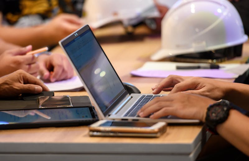 lap-top-pa-bord-ngn-studerar-hjalm-syns-bredvid