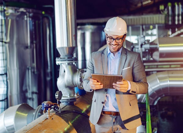 person-i-kostym-inom-industrin-hjalm-pa-huvudet