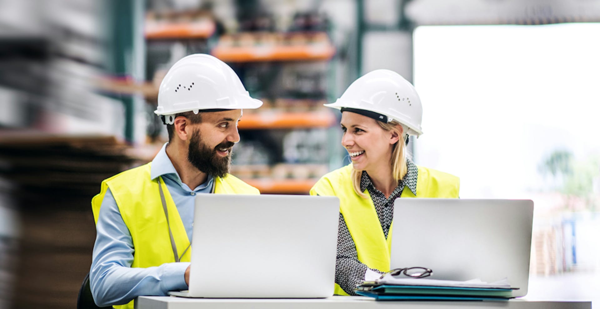 tva-personer-med-hjalmar-bakom-tva-lap-tops-ler-