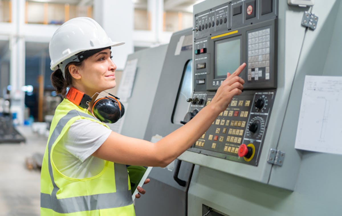 kvinna-med-hjalm-vid-cnc-maskin-inom-industrin