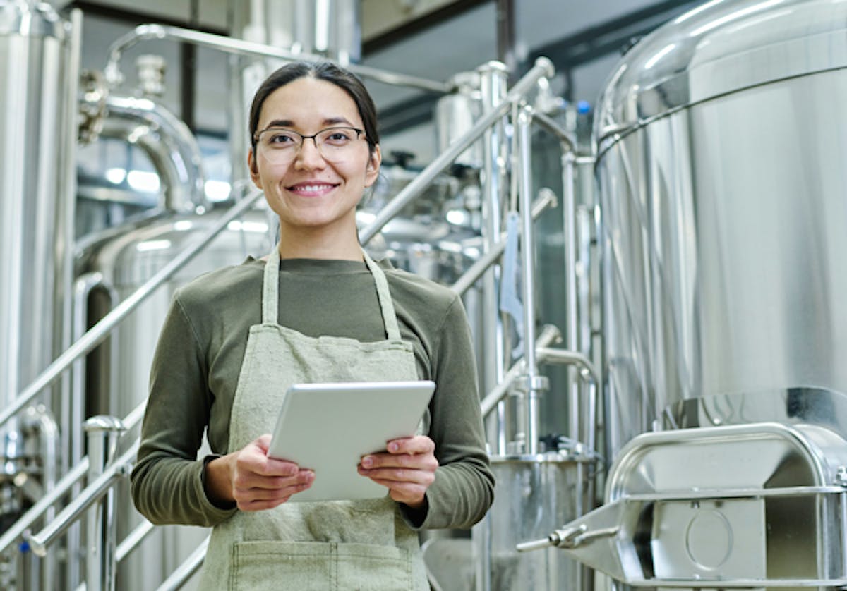 person-med-device-i-handen-star-med-cisterner-i-bakgrunden