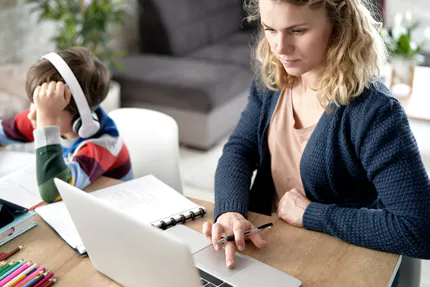 kvinna-studerar-med-barn-bredvid-sig-som-har-headphones