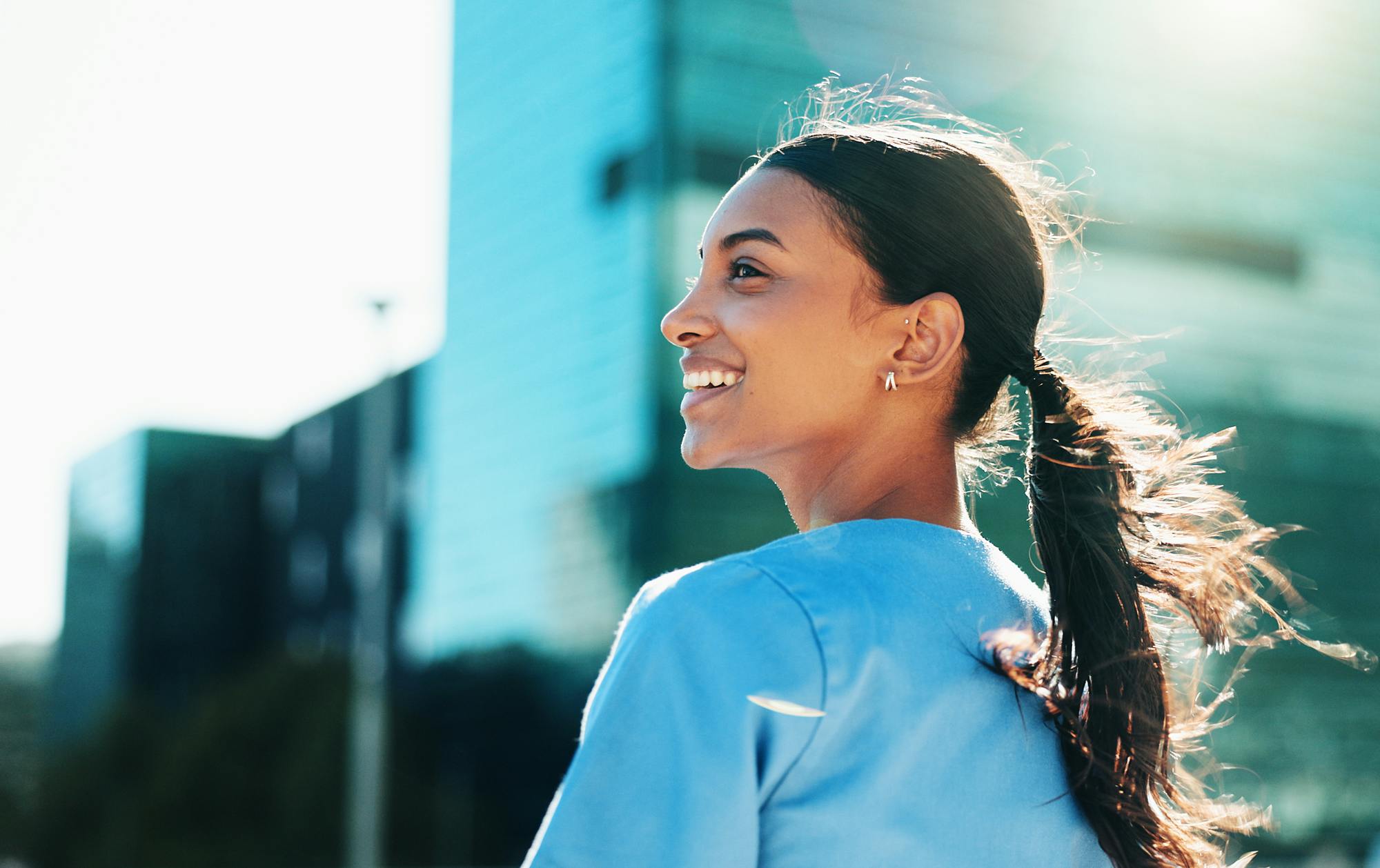 leende-tjej-gar-ute-i-solen-hoghus-i-bakgrunden-2