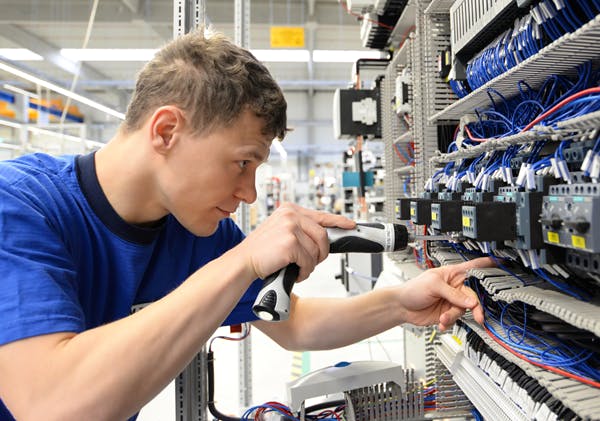 kille-står-och-skrivar-el-komponenter-i-en-vägg