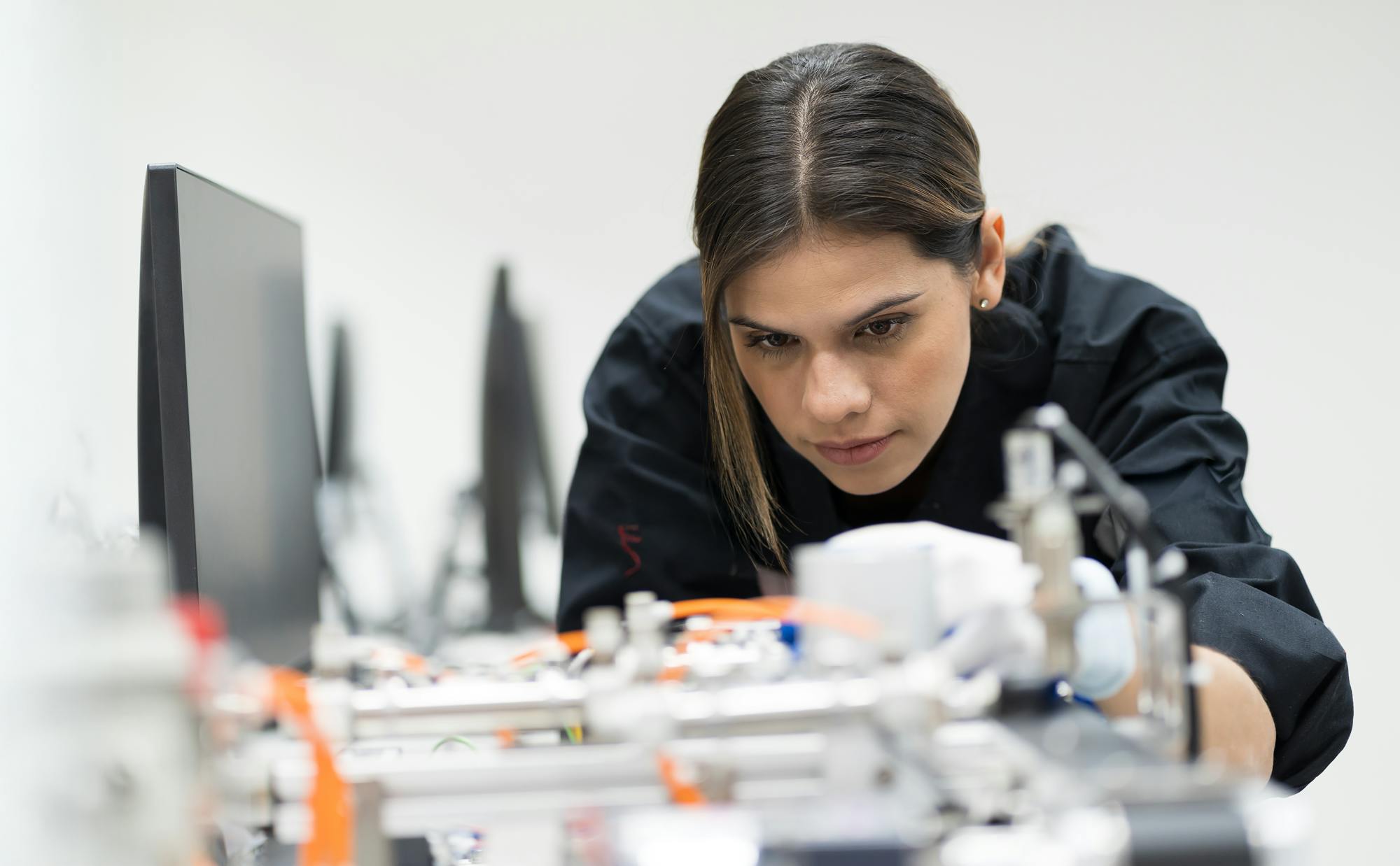 tjej står böjd och koncentrerad över elektriska prylar