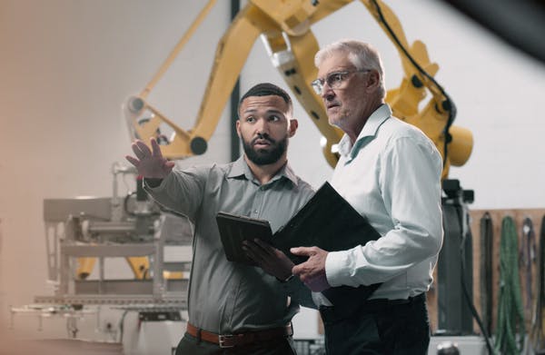 tva-personer-i-industrilokal-en-pekar-runtomkring-maskiner