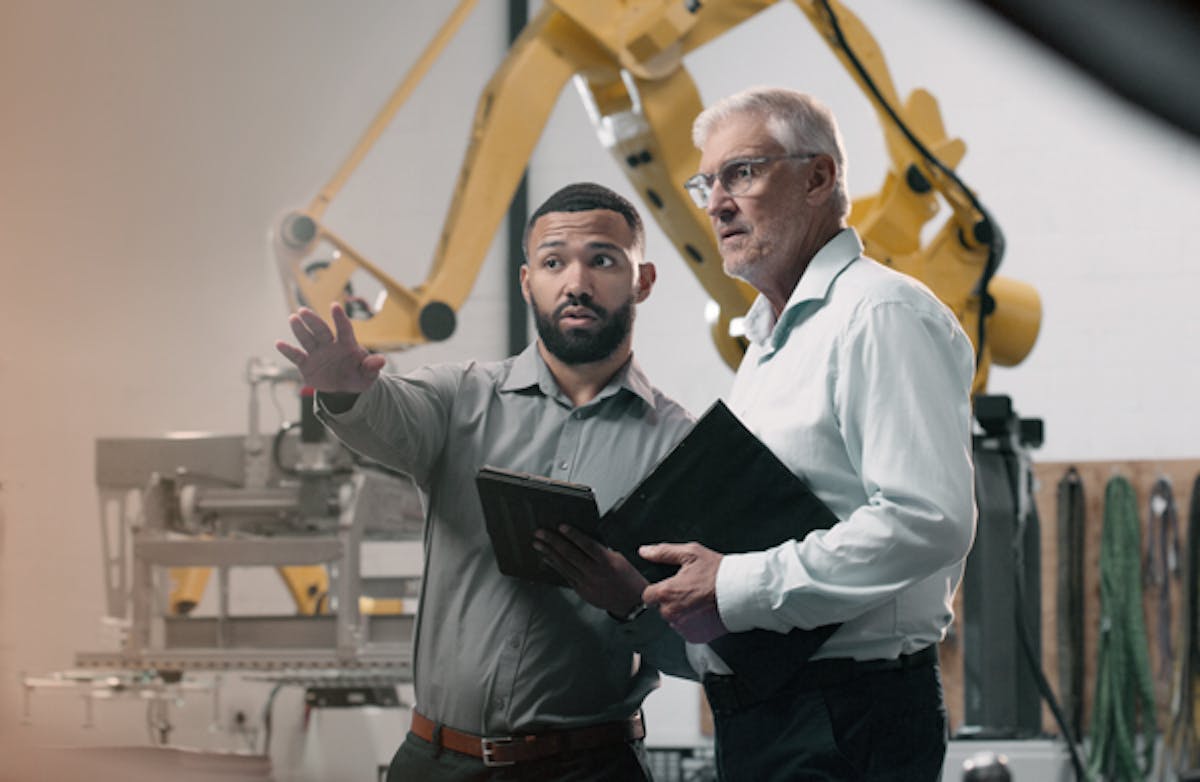 tva-personer-i-industrilokal-en-pekar-runtomkring-maskiner
