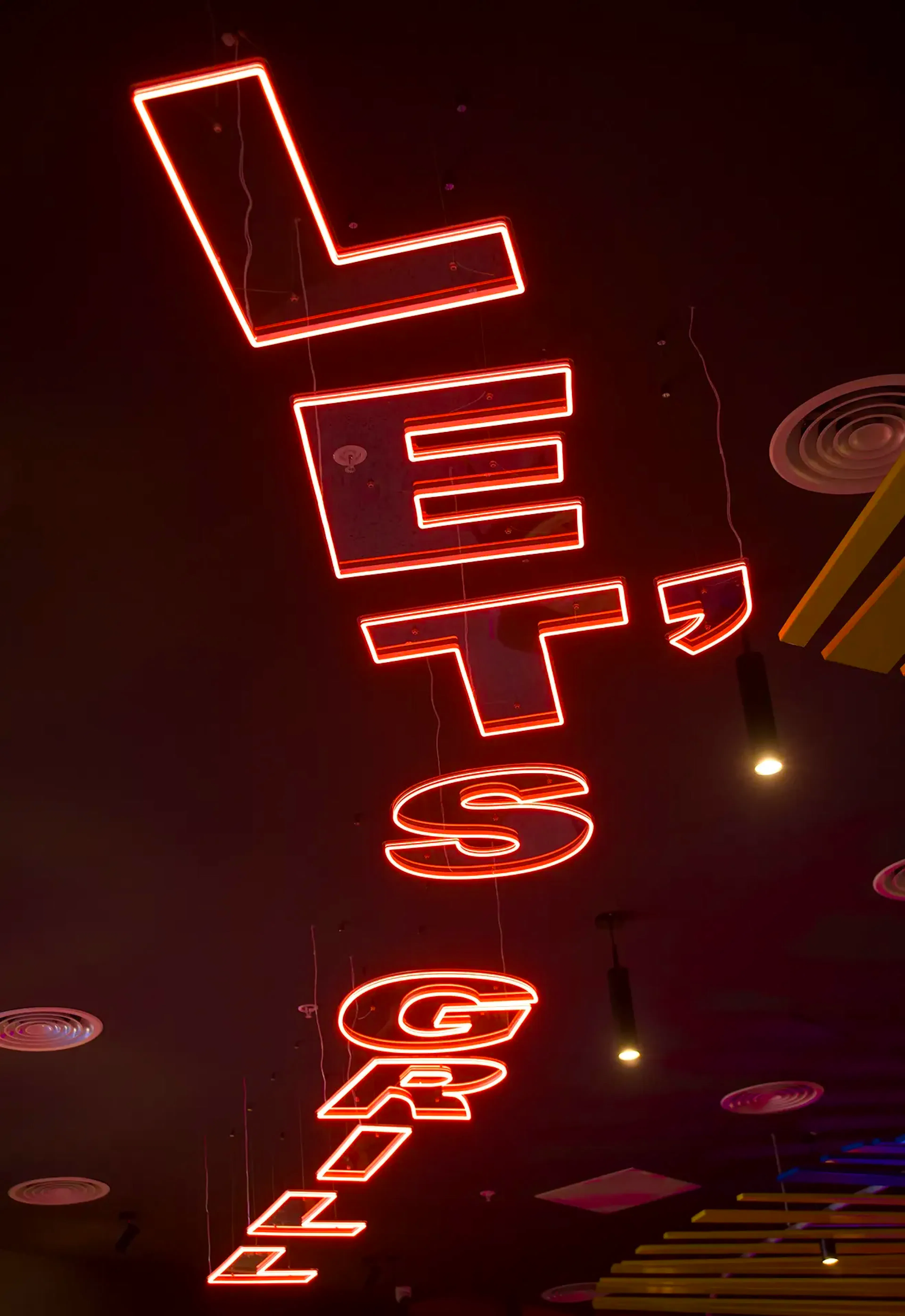 Neon signage displayed vertically along the ceiling