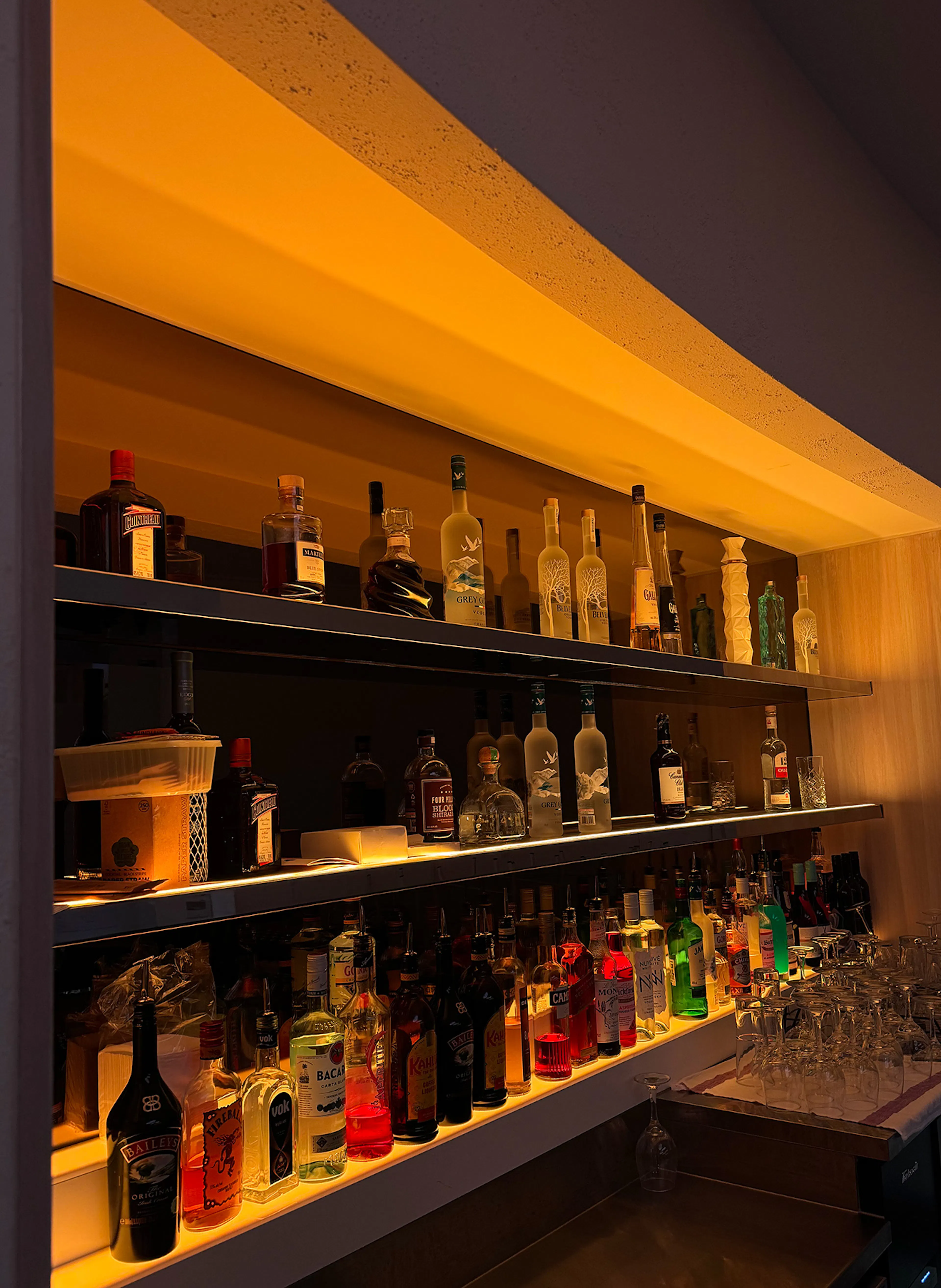 Multi-tier illuminated bar display featuring custom LED shelf lighting and premium spirit bottles