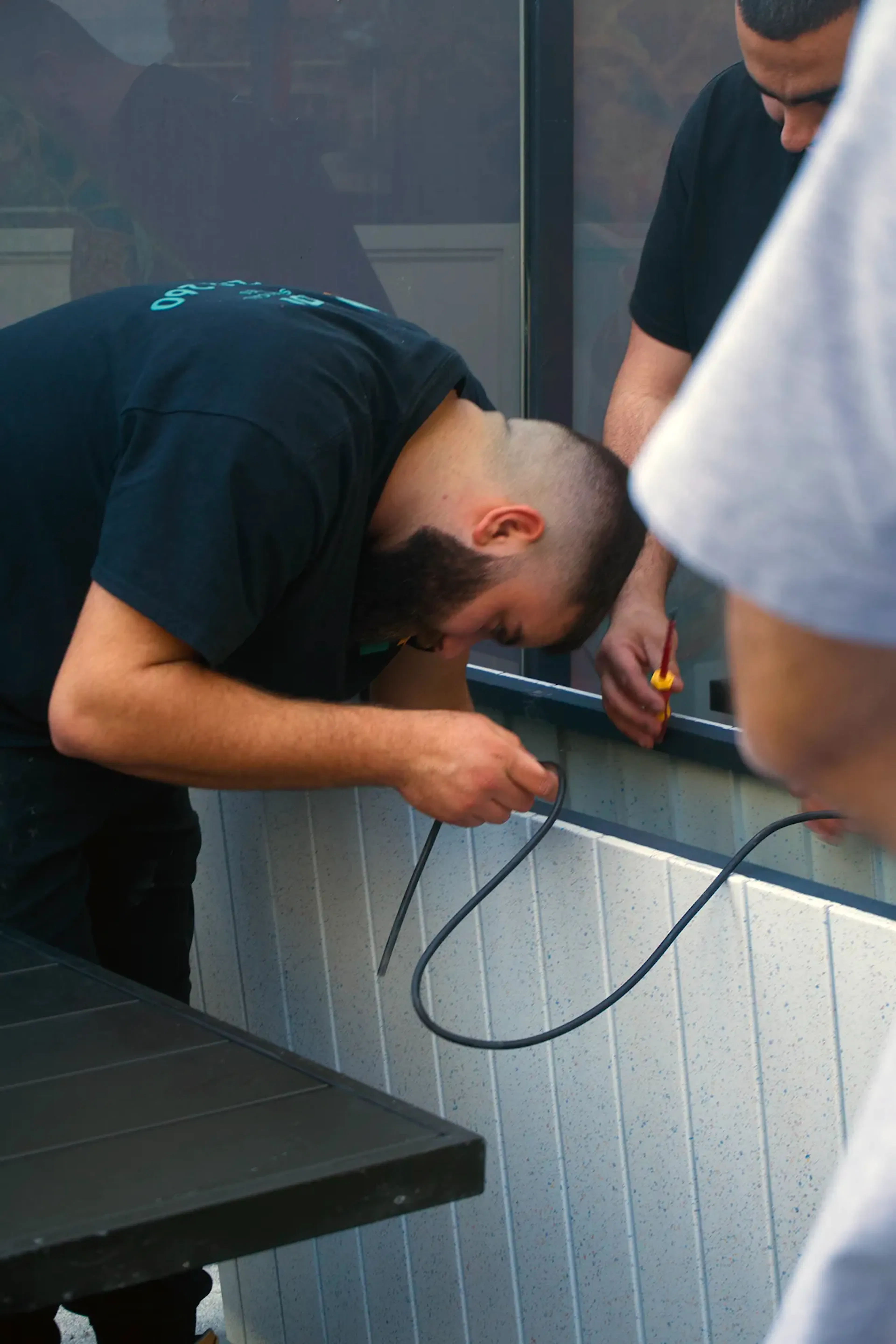 Electrician routing cabling inside a timber counter frame.