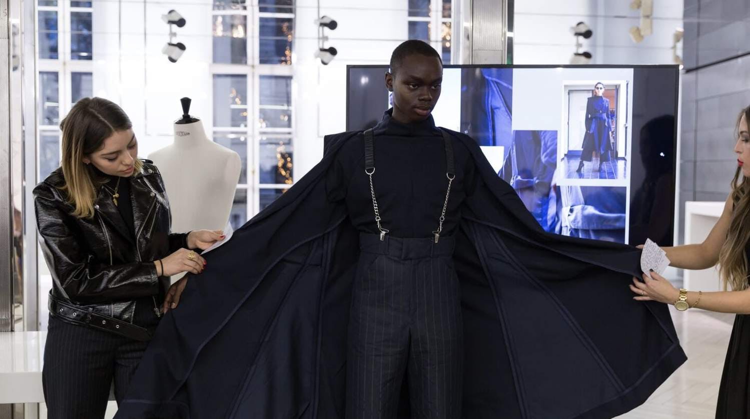 Model being fitted in a new garment by two women for a fashion show