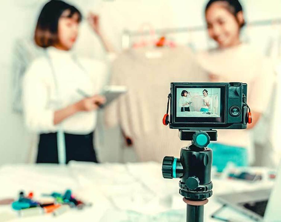 Two women being filmed showing off their own fashion brand