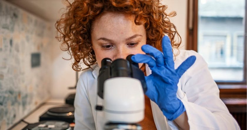 Doctor looking in microscope for cancer research