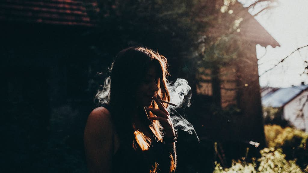 Frau raucht einen Joint im Garten