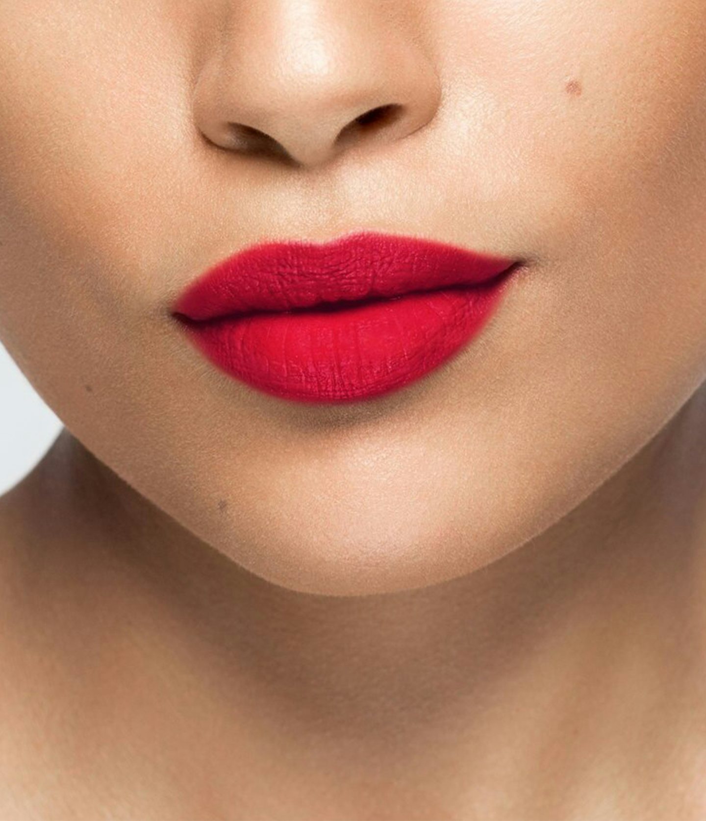 La bouche rouge rouge à lèvres 70s America sur les lèvres d’un mannequin à la peau au teint moyen 