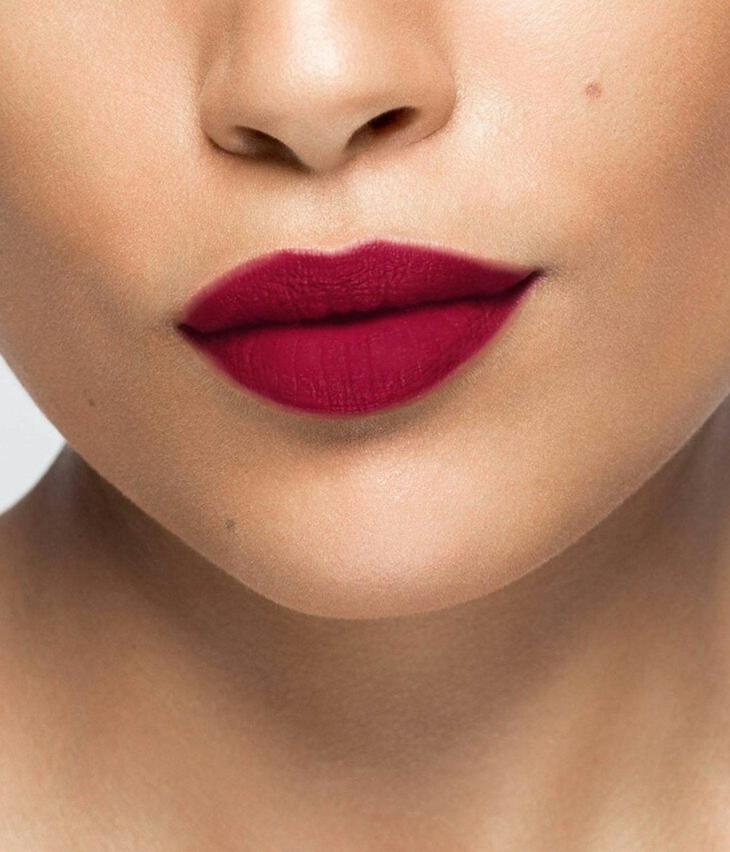 La bouche rouge rouge à lèvres Burgundy sur les lèvres d’un mannequin à la peau au teint moyen 