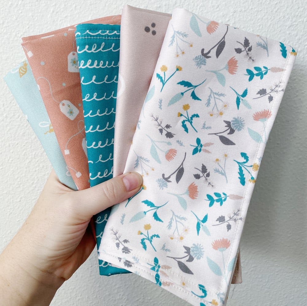 A hand holding cloth napkins of different patterns