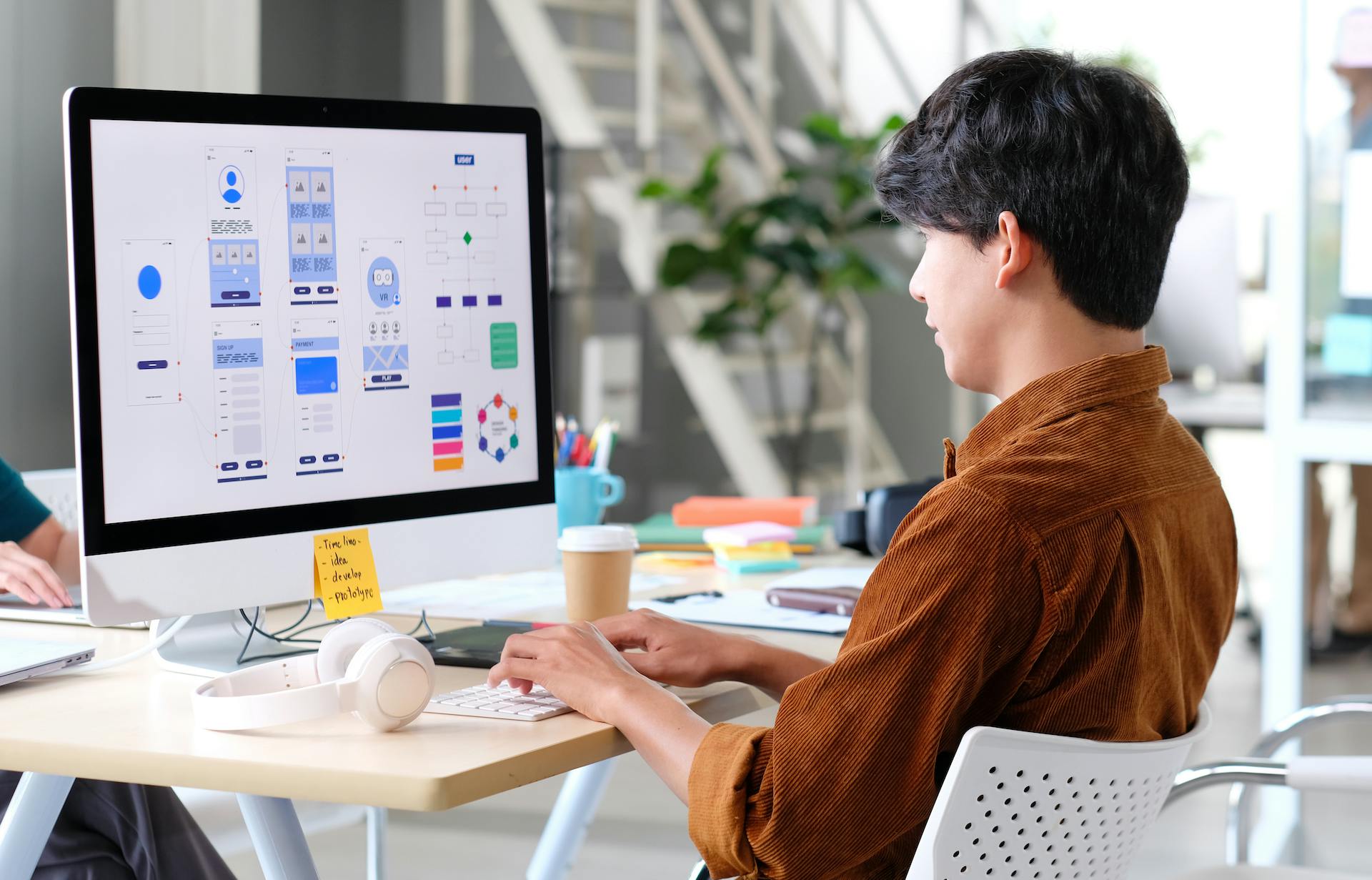 Designer working on a desktop computer with multiple app wireframes displayed, symbolizing the creativity and innovation behind AI startups you need to know about.
