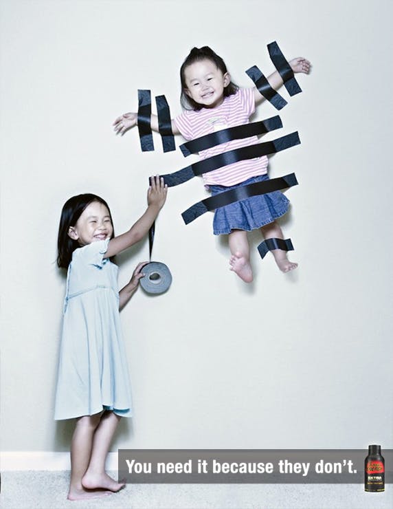 One Asian child taping another to the wall