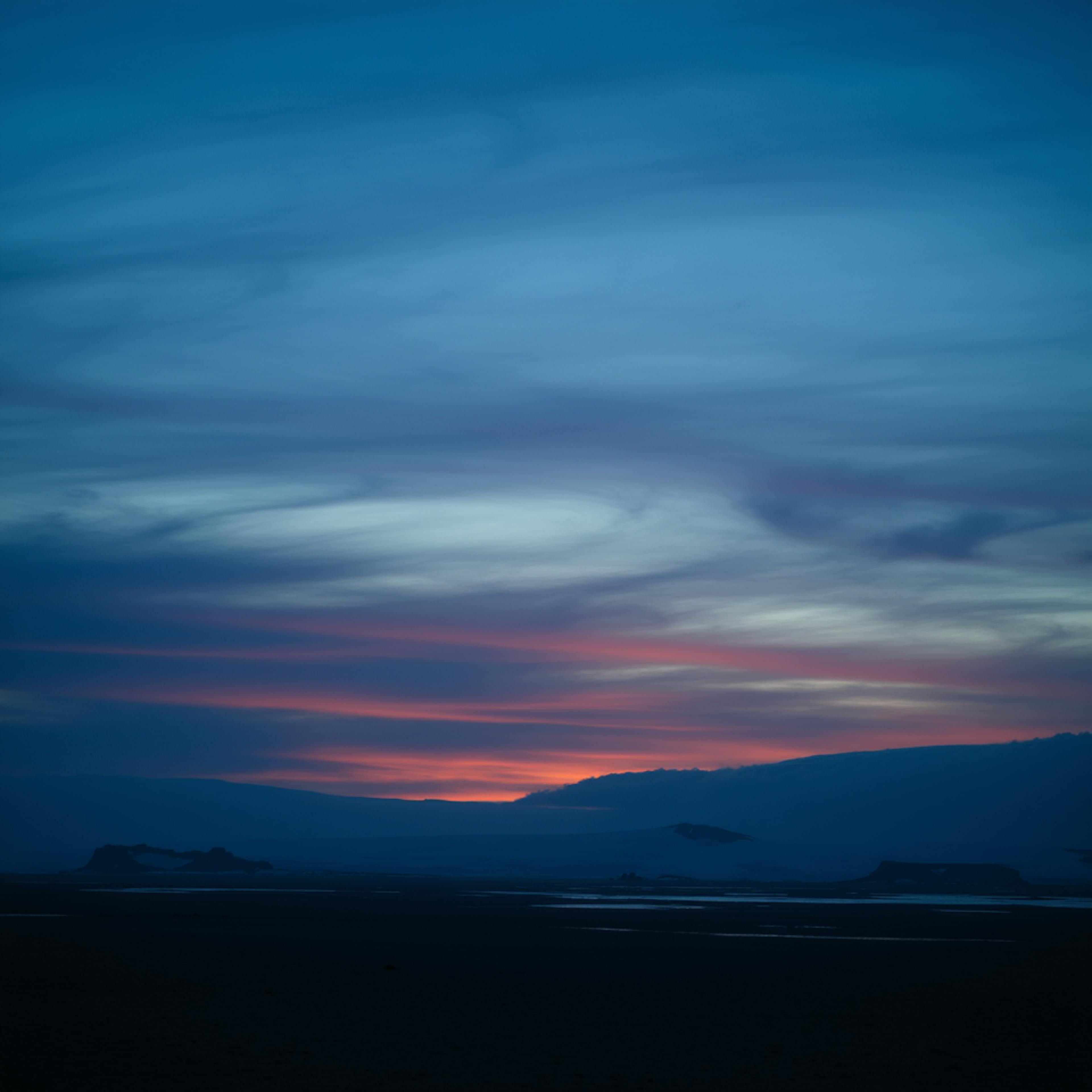 A peaceful twilight scene with flowing blue and pink tones in the sky, capturing the harmony of monochromatic color schemes in the landscape.