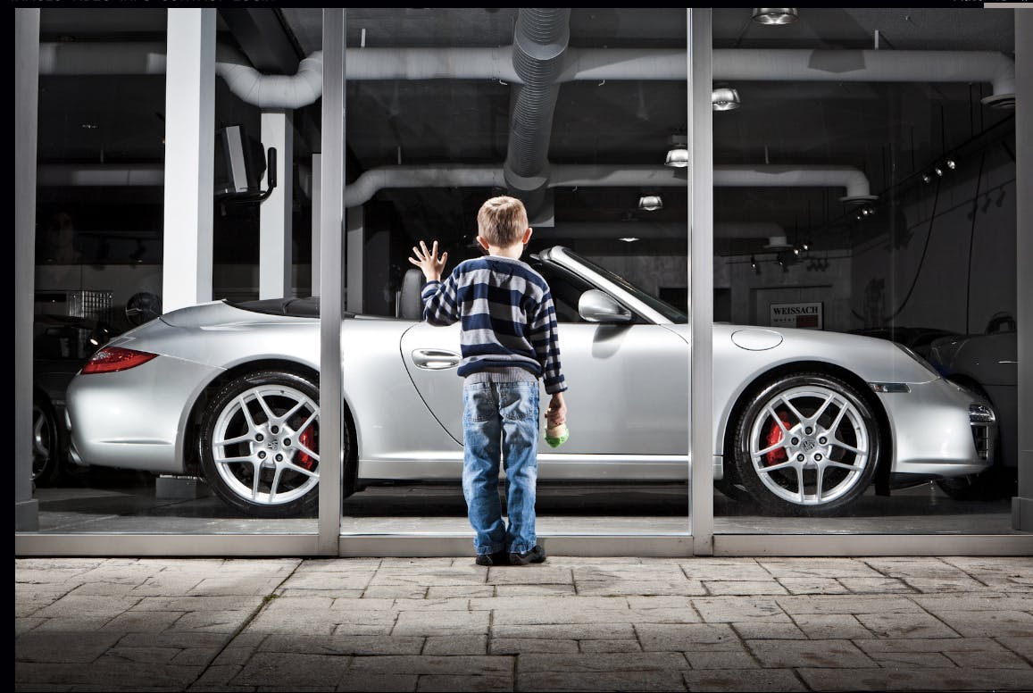Photograph of a boy looking at a Porsche