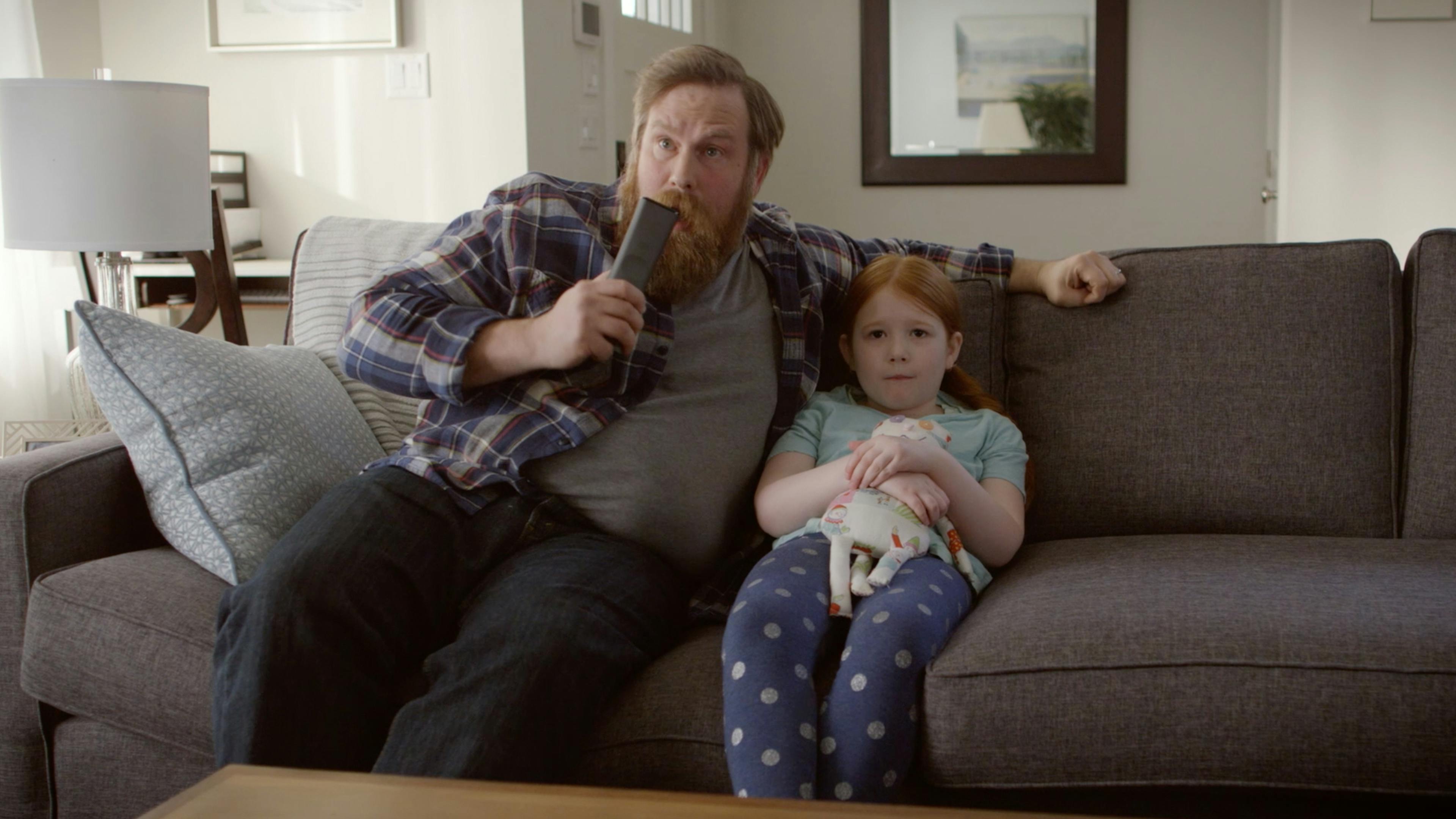 Father and daughter on couch watching tv