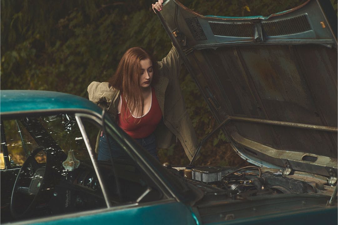 A woman looking at a car engine