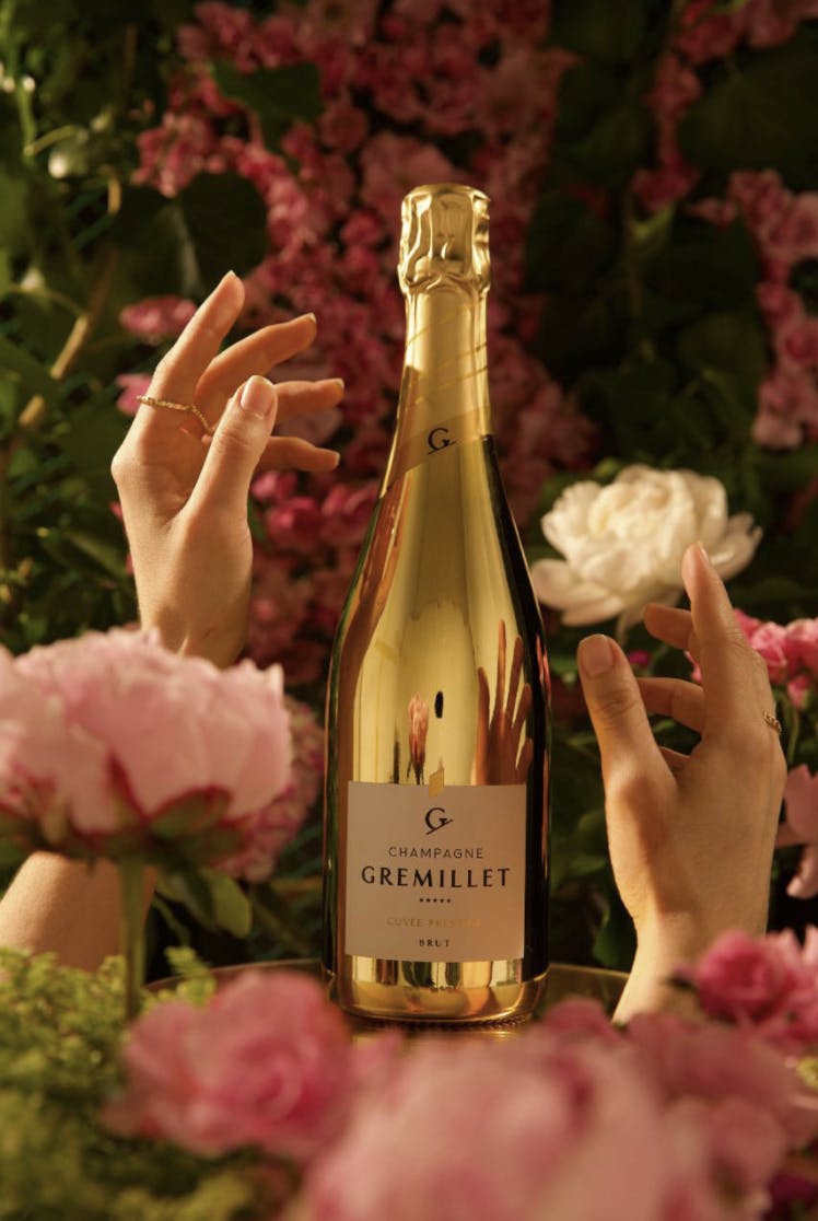Hands reaching for golden bottle of wine