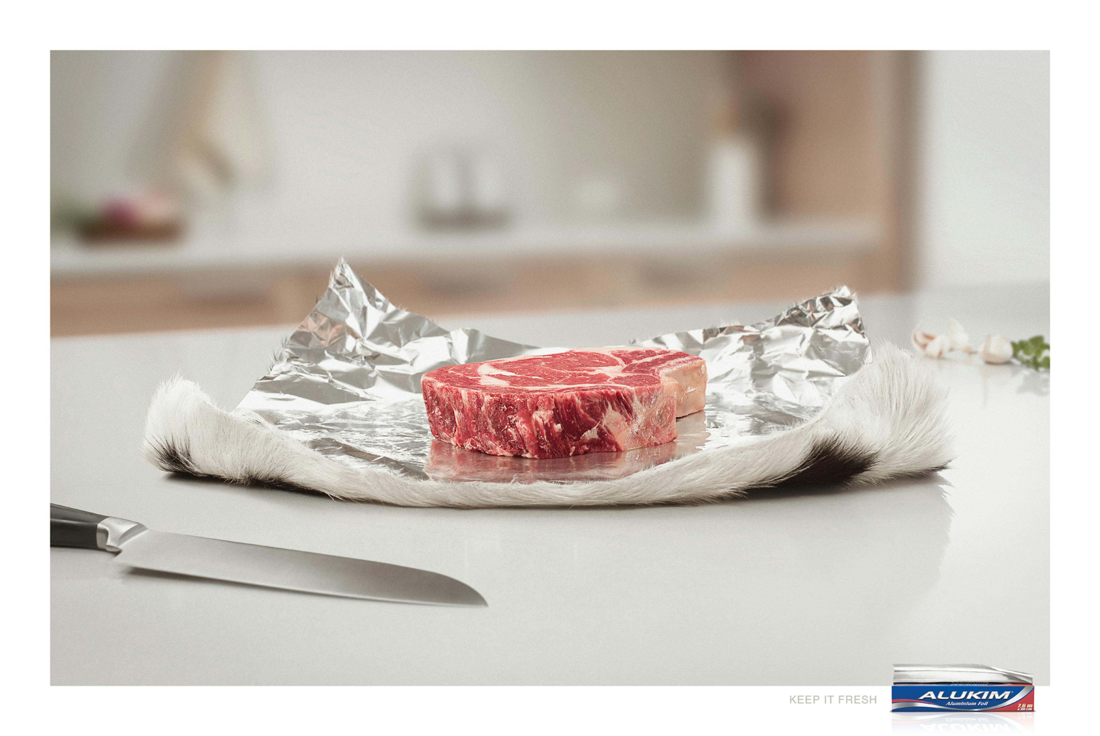 Raw steak on aluminum foil on a countertop